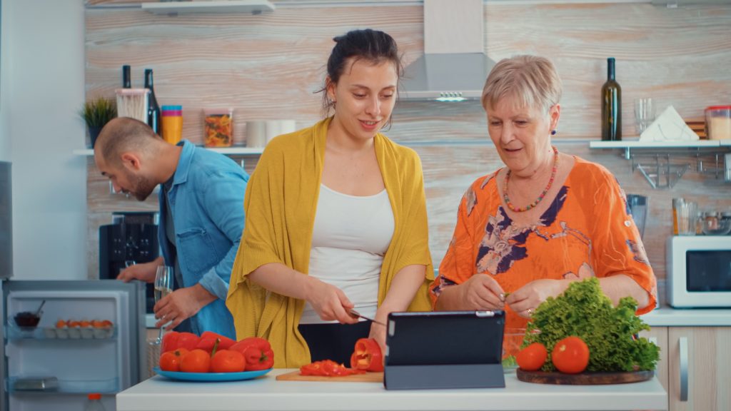 Support worker teaching an NDIS participant life skills during a cooking activity at home